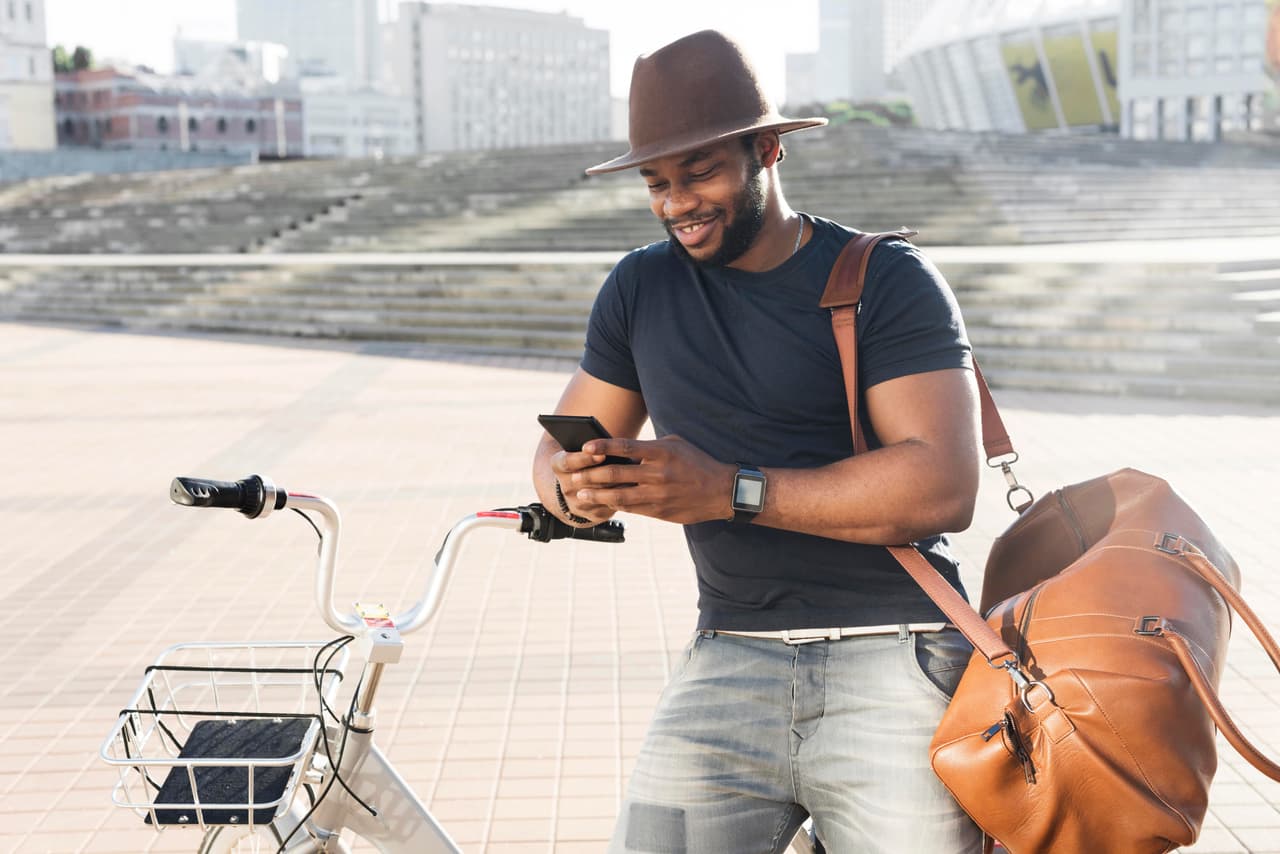 Man checking his phone while leaning on a bicycle